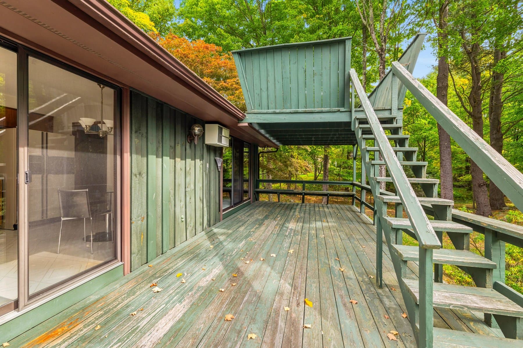 The wood deck along the back of the house, with the sliders into the living room and the stairs down to the lawn