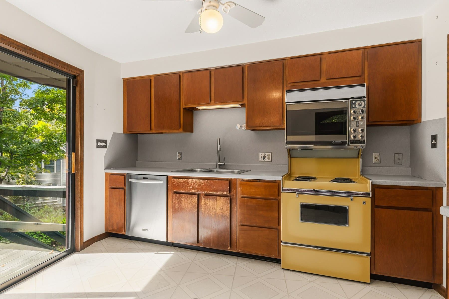 The kitchen counter run with the sink under a window, the wall oven and microwave, and the electric range