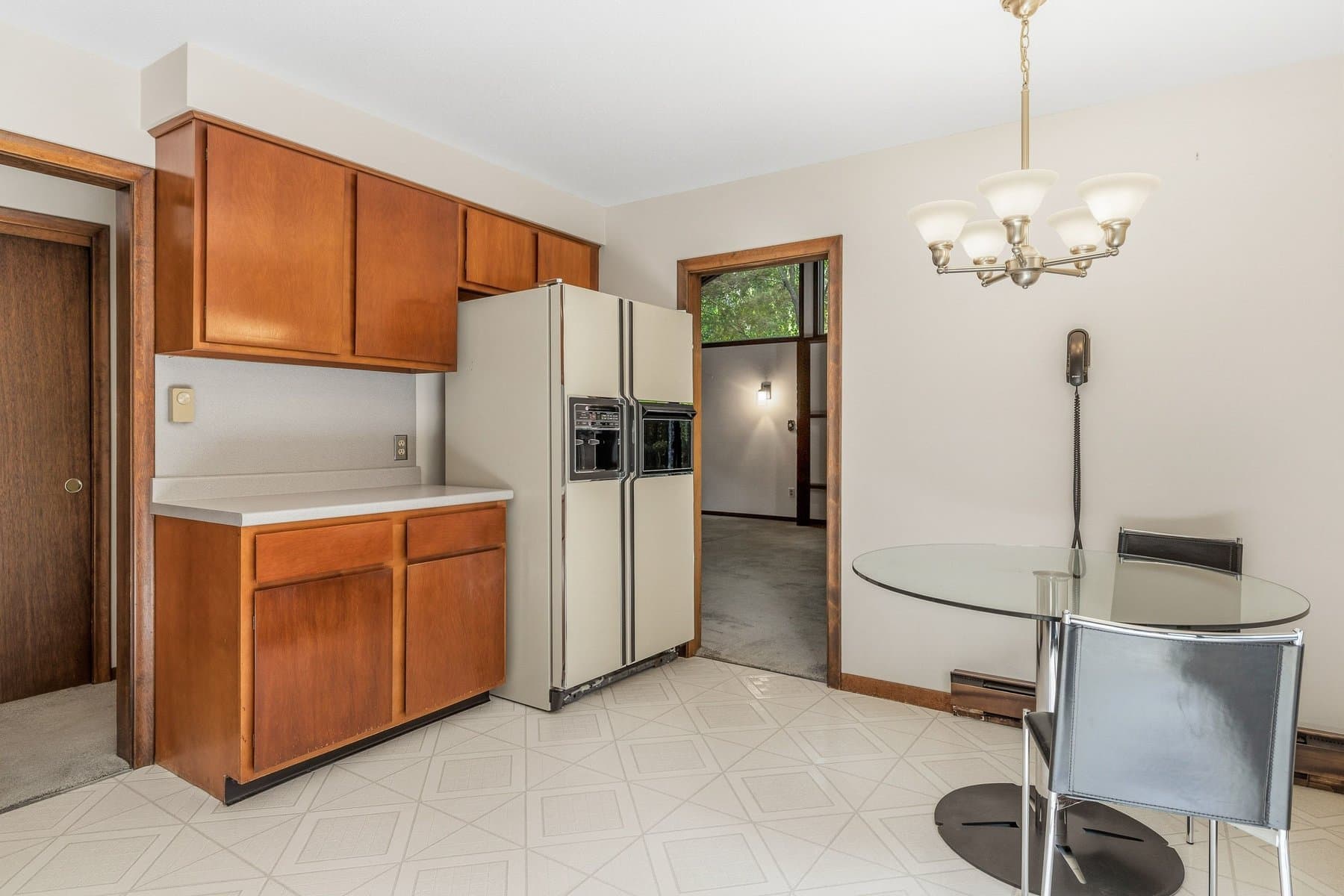 The refrigerator side of the kitchen, with the dining table and the doorway through to the living room